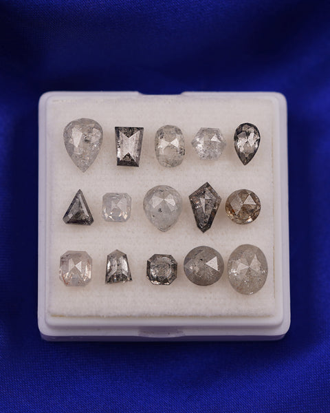 Three rows of salt and pepper diamonds of various shapes and cuts in a white box