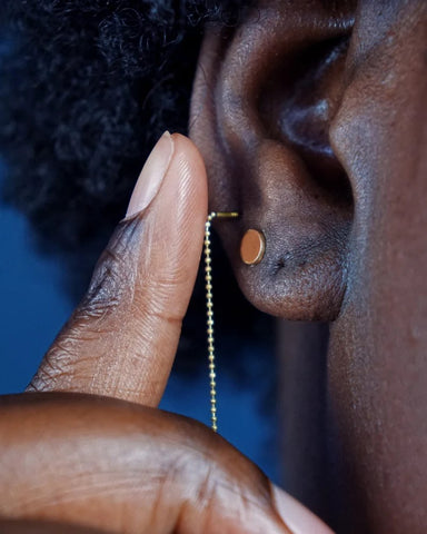 A model pushing a threader into their piercing incorrectly by bending the beads at the post