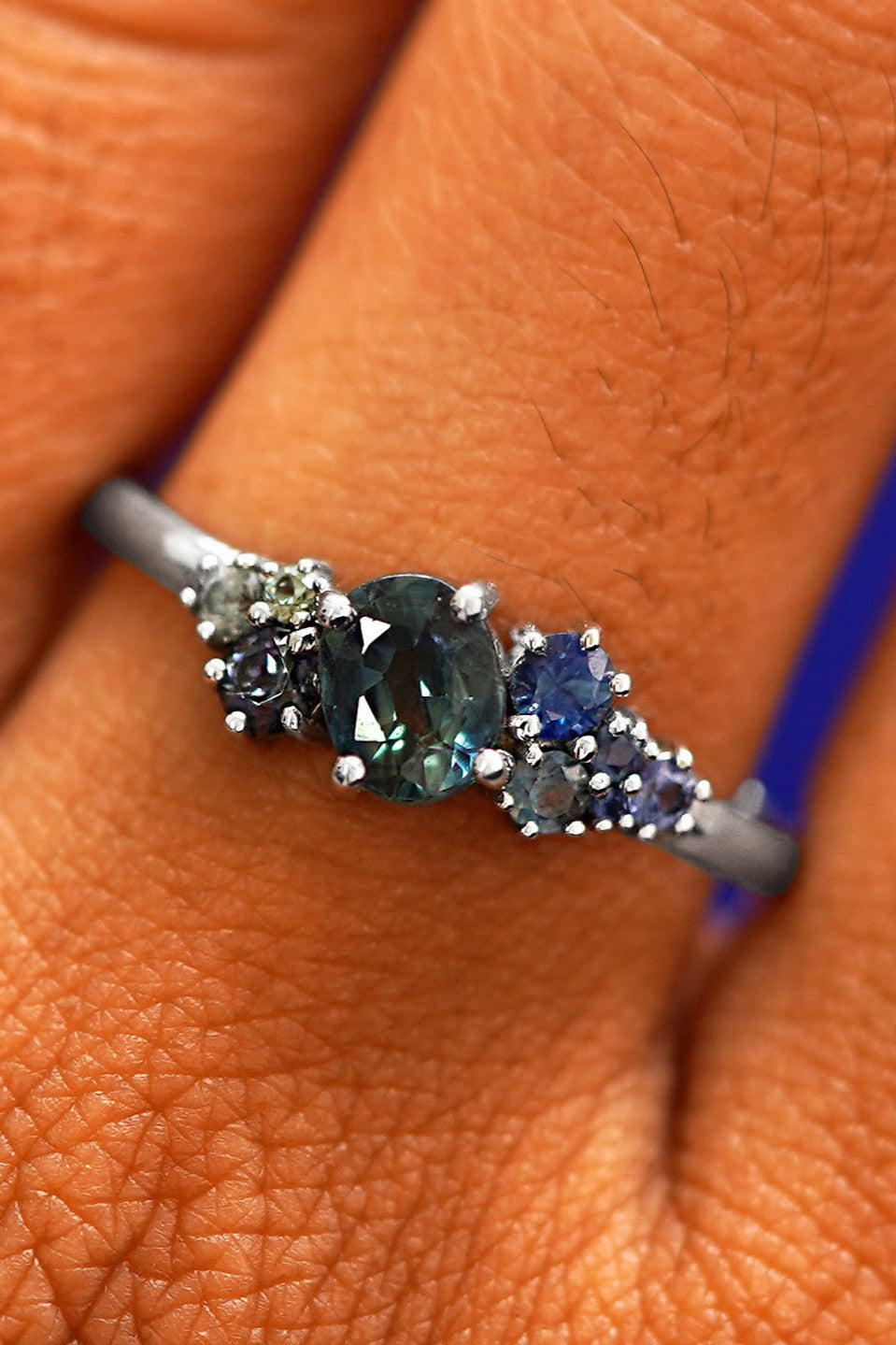 Close up view of a model's hand wearing a 14k white gold sapphire cluster ring