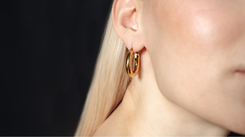 A close-up shot of a pair of gold studs