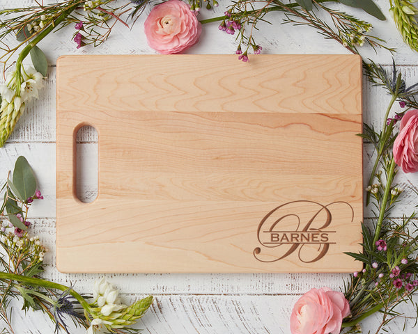 Engraved Maple cutting board with pink roses and greenery surrounding it.