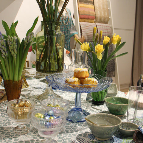 Easter table setting with cake stand, ceramic bowls, vases and flowers 