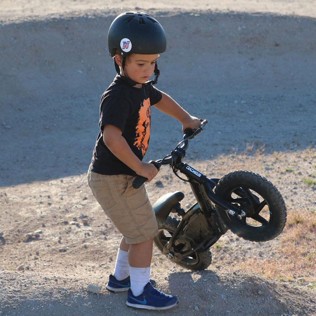 little boy lifting its electric balance bike