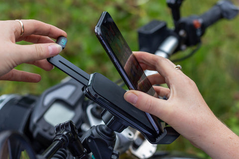 Woman placing a phone into a holder on motorcycle handlebars