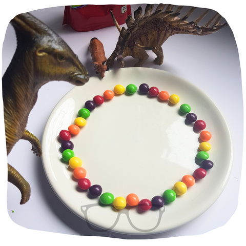 Rainbow candy is placed around the plate, the dinosaurs are watching very carefully.