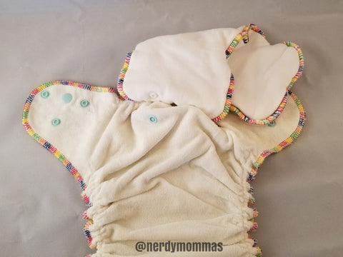 flatlay photo of a "hybrid/AI2" cloth diaper. removeable insert attaches to waterproofed cover via snaps