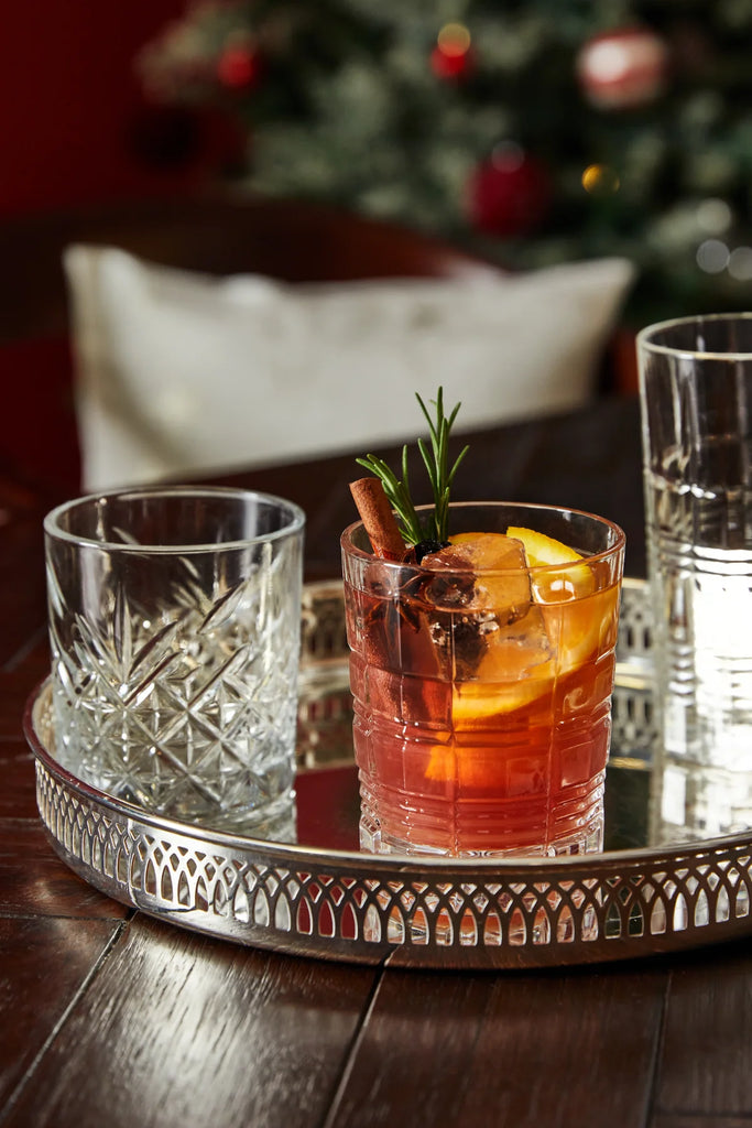 cocktail natalizio con cannella, rosmarino, fetta arancia su vassoio argento