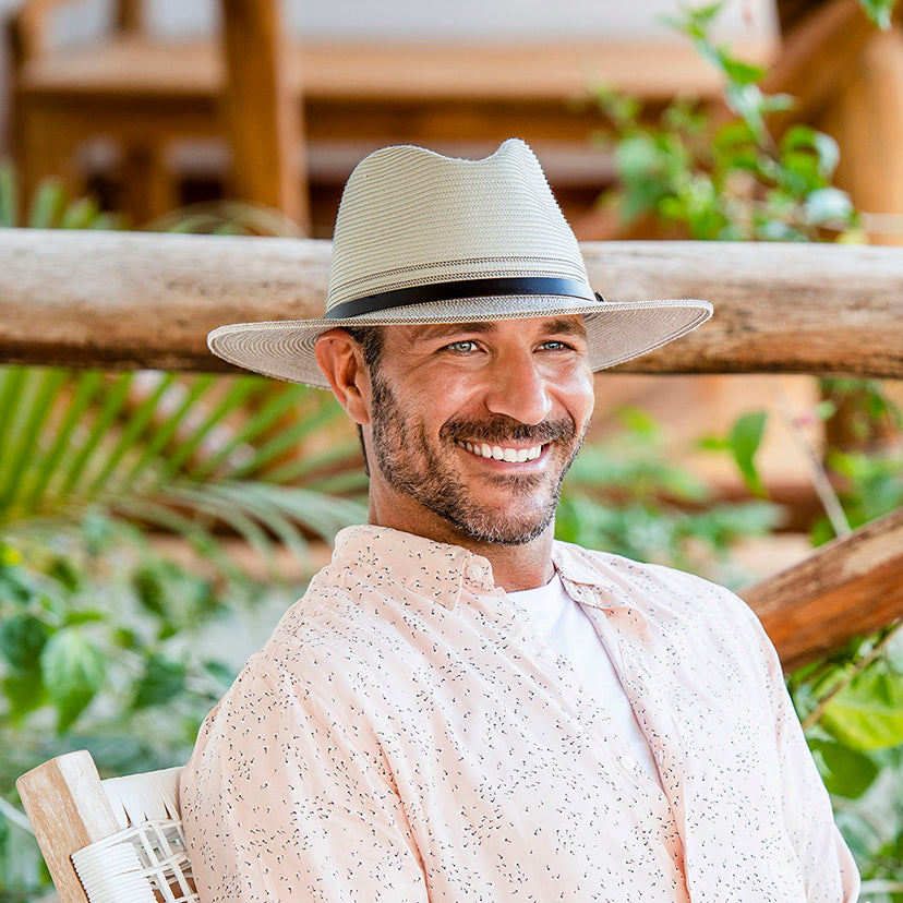 Man Sitting in a Chair Wearing a Wallaroo Carter, a UPF travel Summer cap