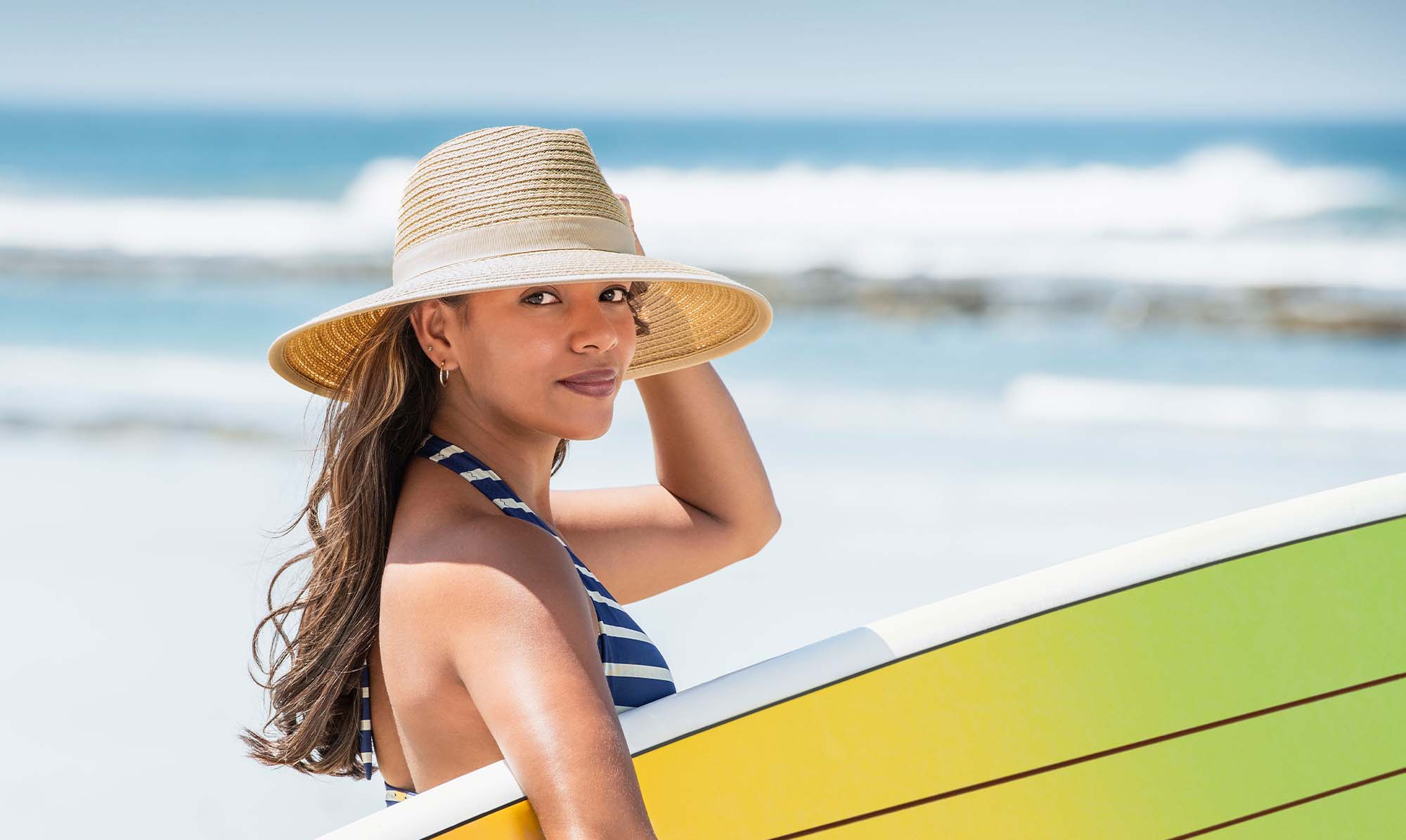 Woman with a Surfboard Wearing the Wallaroo Bali Beach Sun Hat with a big wide brim