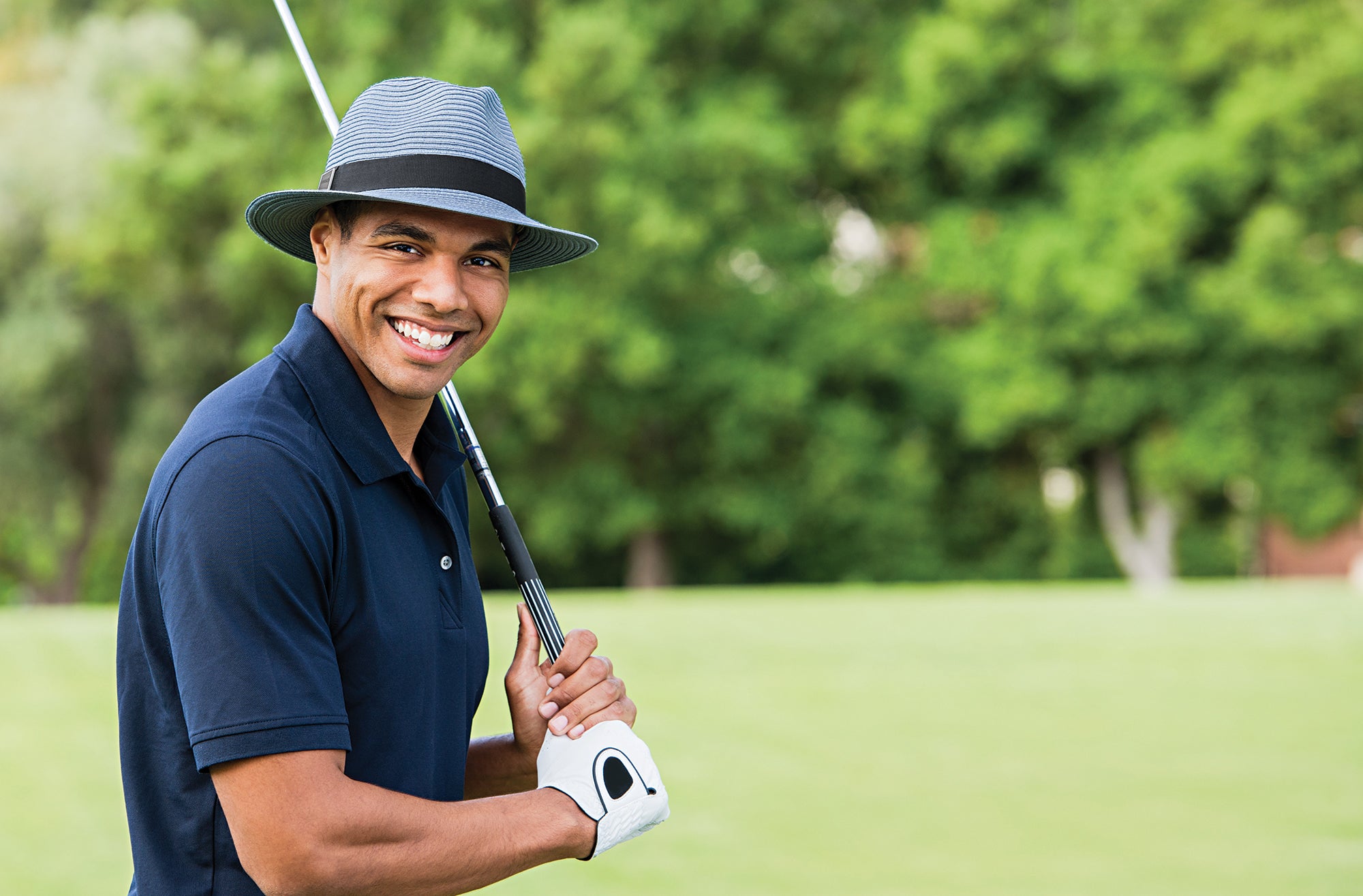 Man ready to swing a golf club on the course standing Wearing a Carkella Fairway Summer Sun hat 