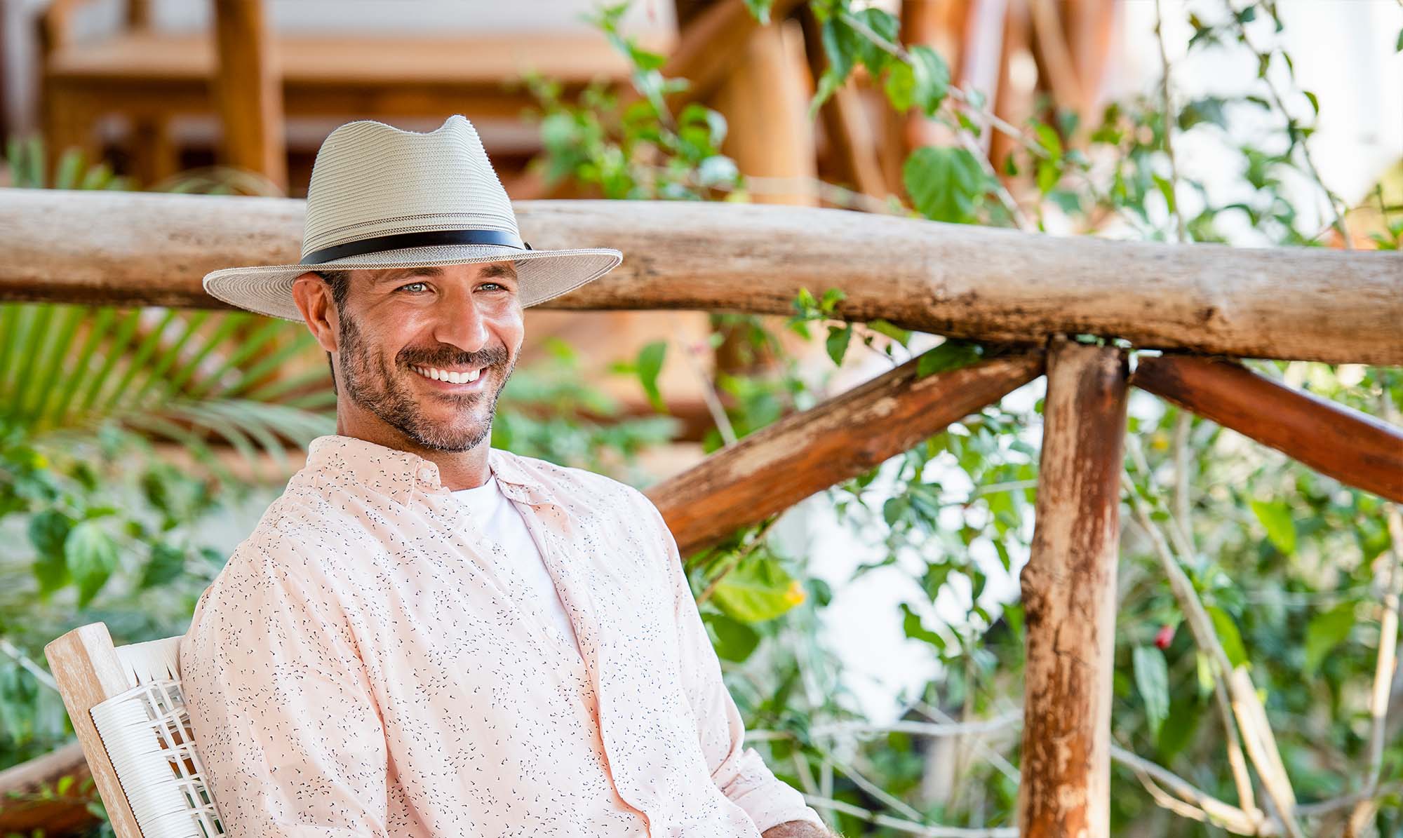 Man Sitting in a Chair Wearing a Wallaroo Carter, a UPF travel Summer cap