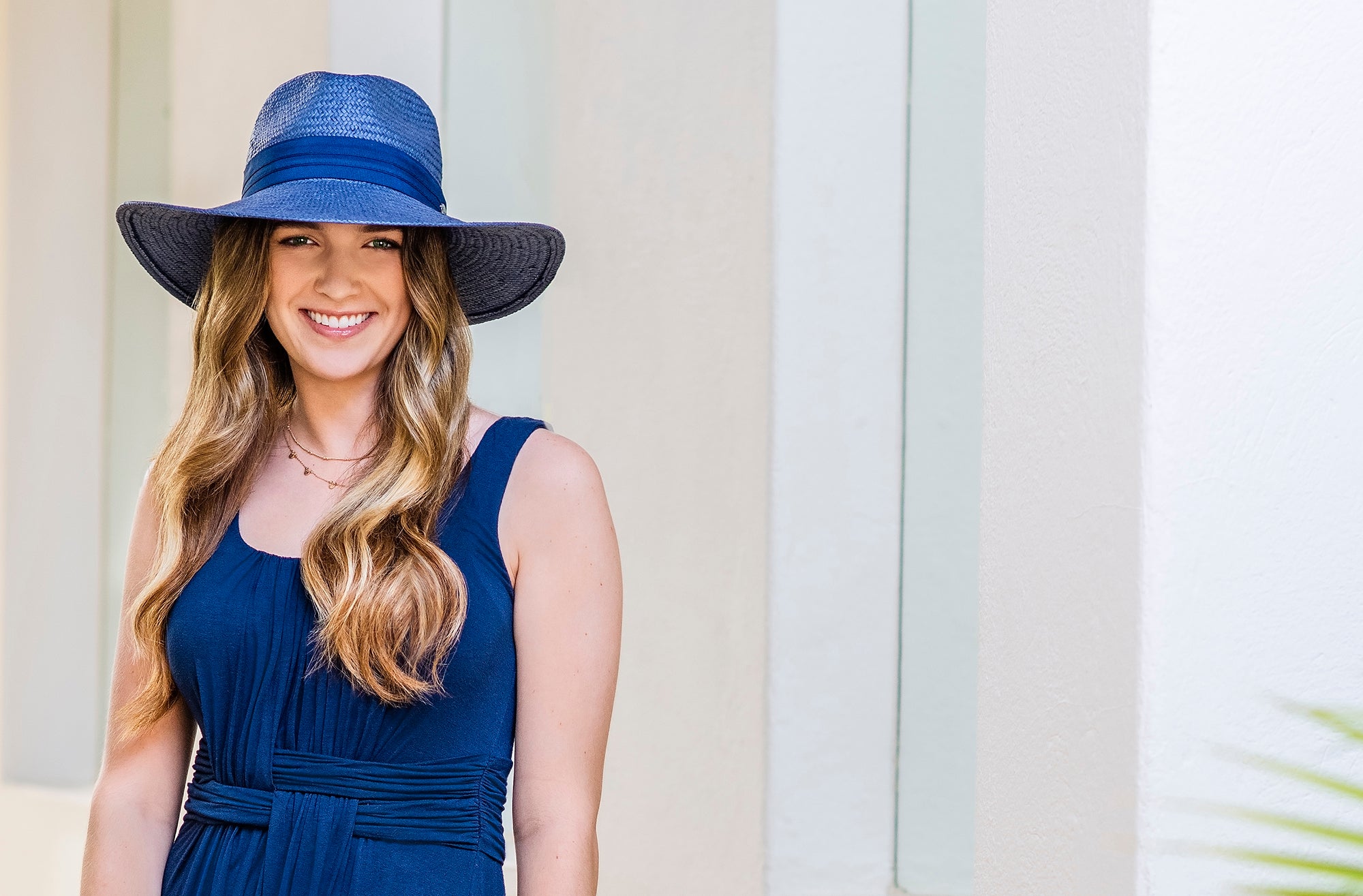 Woman wearing a big wide brim Klara straw summer sun hat with a UPF 50+ rating