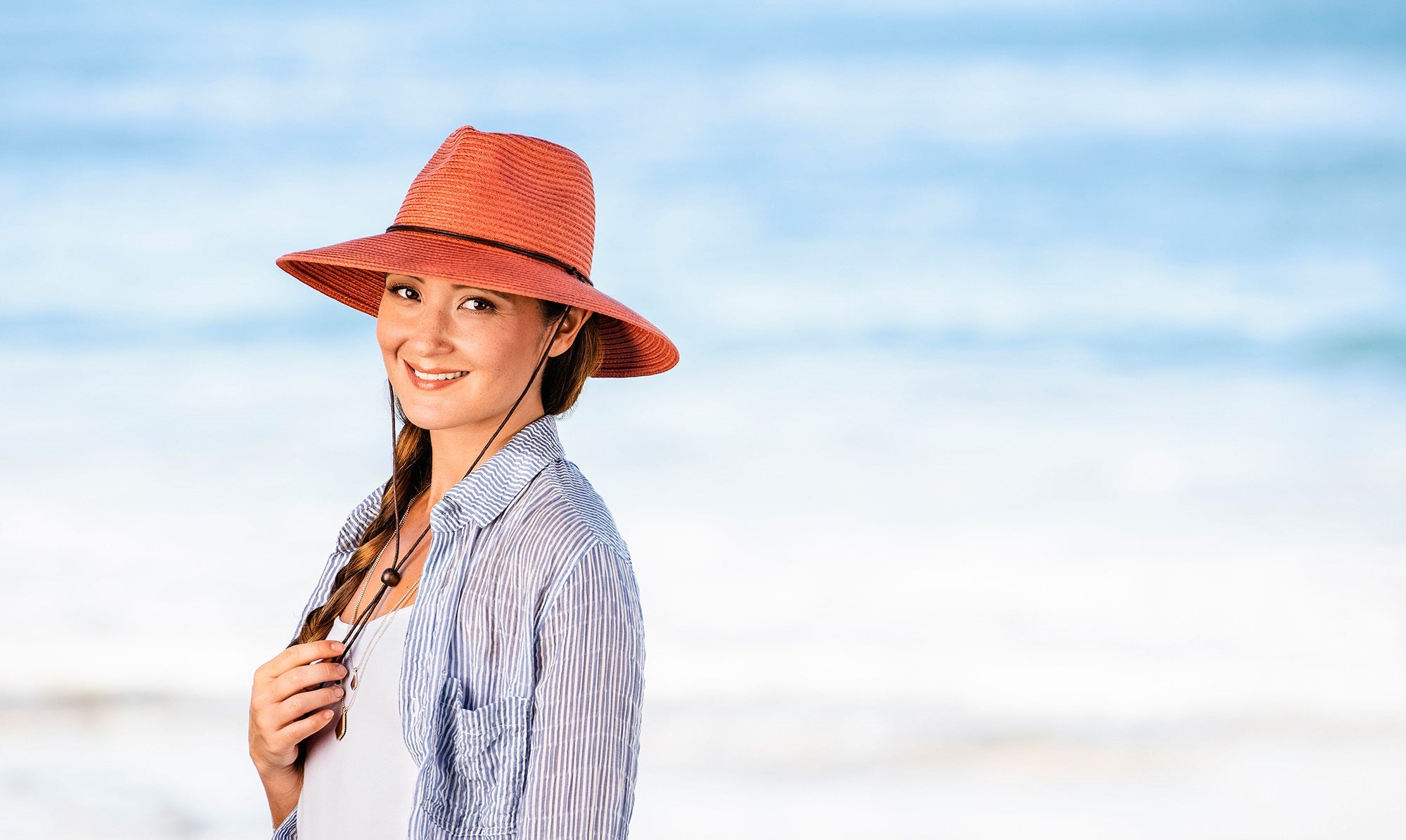 Woman Wearing a Wallaroo Petite Sanibel Summer Sun Hat with uv protection while on the beach