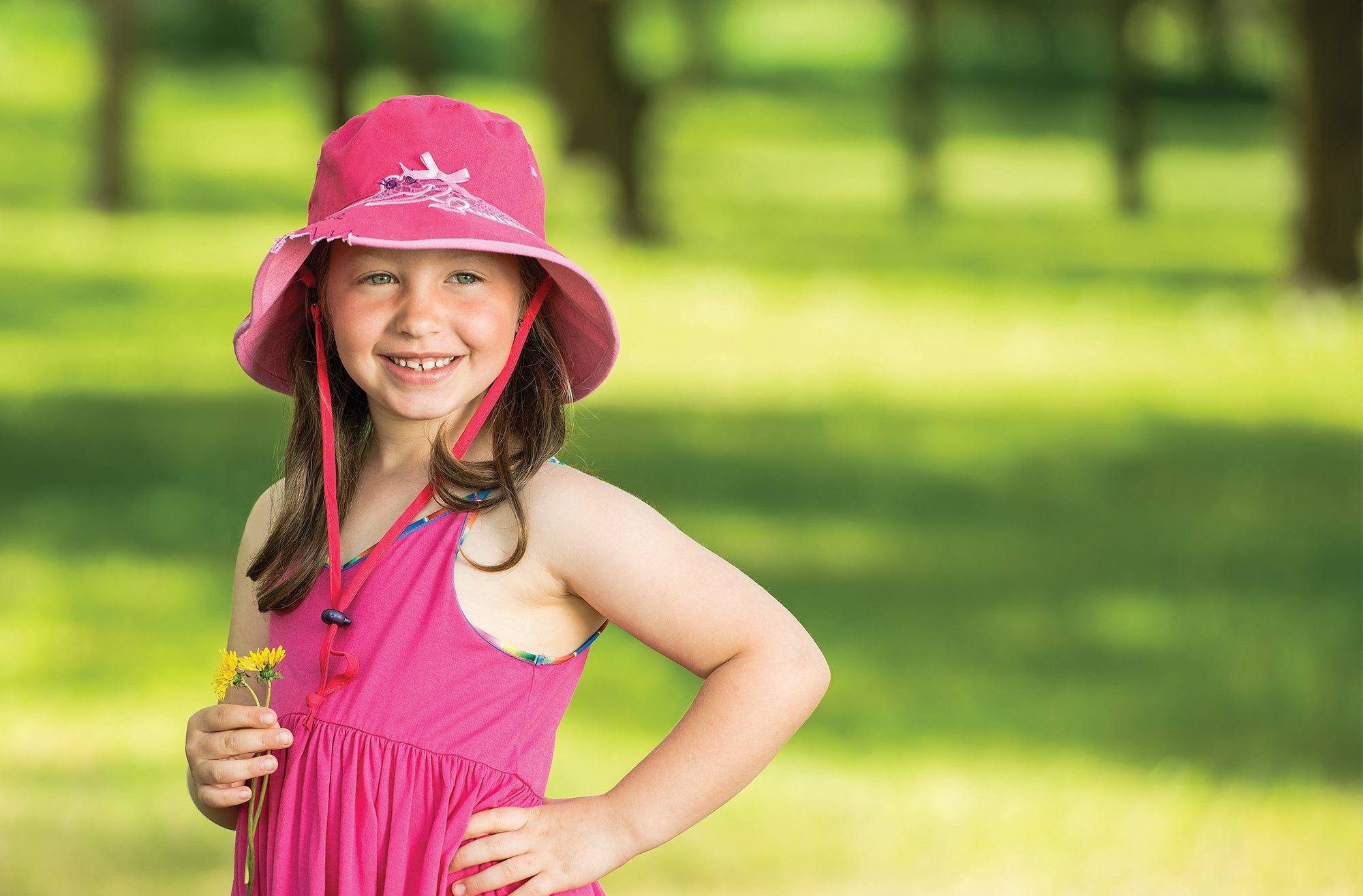 Girl Wearing a Wallaroo Crocodile Cotton Sun Hat with Chinstrap while Holding a Flower