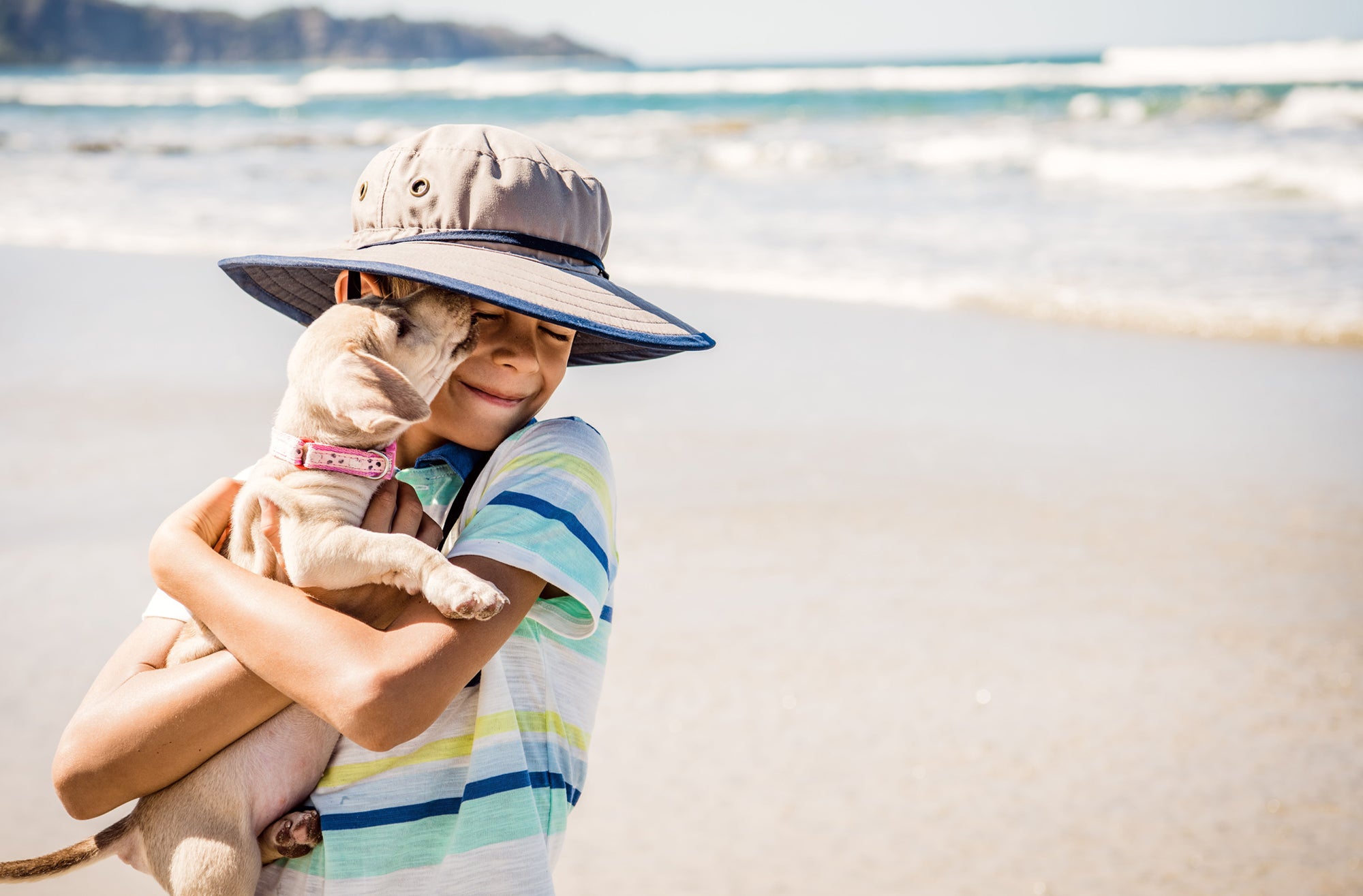 Boy Wearing a Wallaroo Jr. Explorer Microfiber Sun Hat with Chinstrap while Holding a Dog