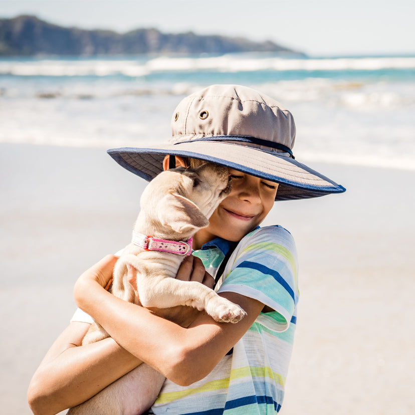 Boy Wearing a Wallaroo Jr. Explorer Microfiber Sun Hat with Chinstrap while Holding a Dog