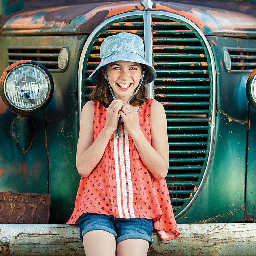 Girl Wearing a Wallaroo Riley Cotton Sun Hat with Chinstrap Sitting on a Car