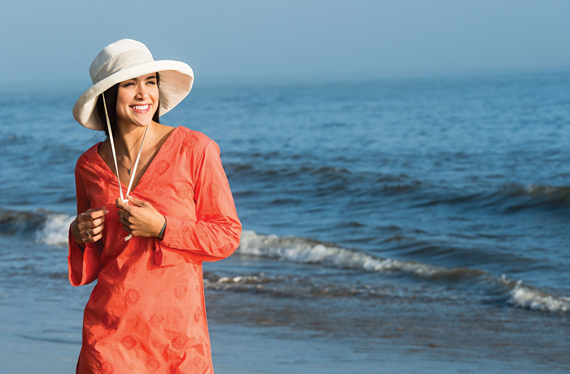 Woman Wearing a Wallaroo Seaside beach Sun Hat with Chinstrap next to a Sea