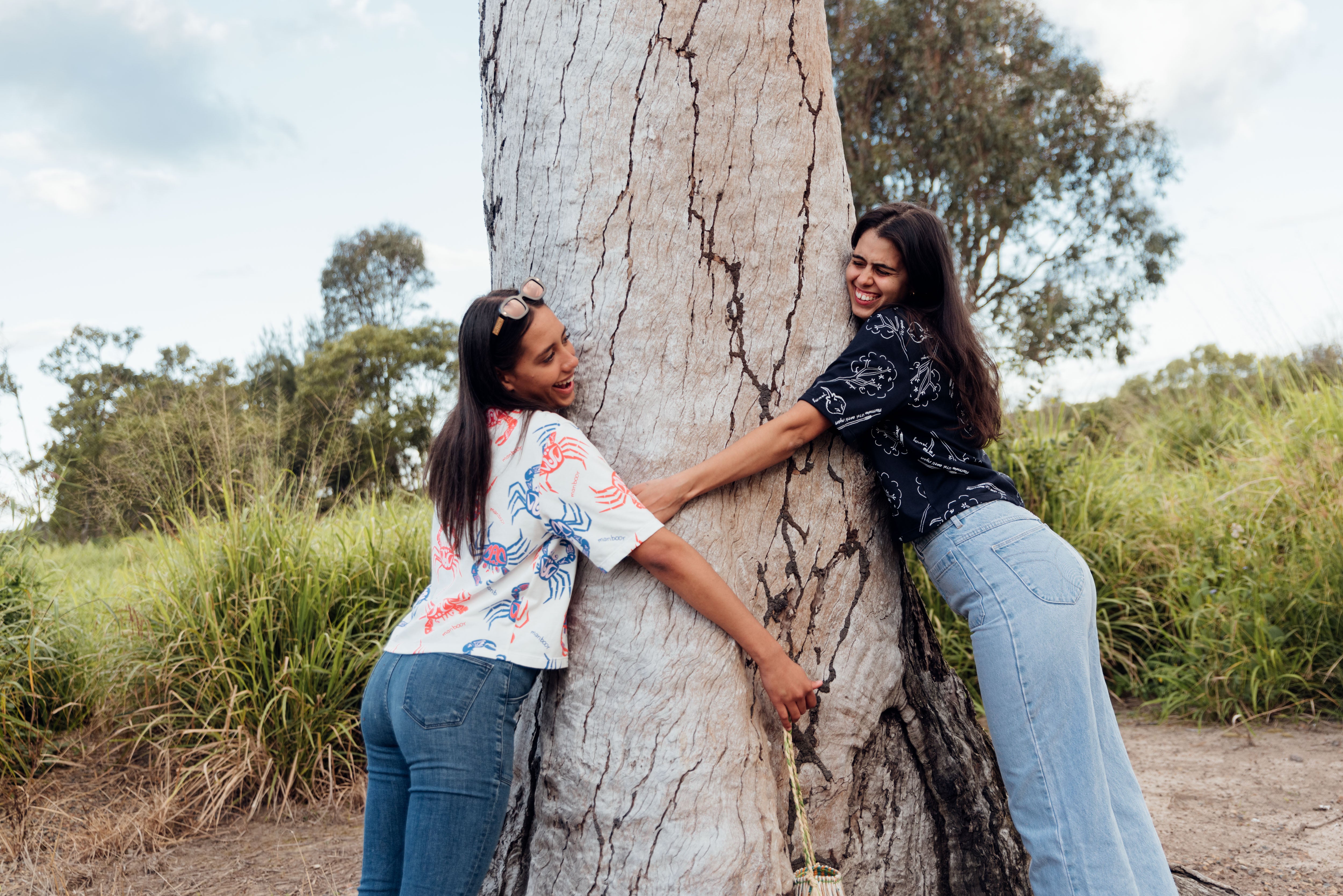 Two models hugging a tree in their t-shirts