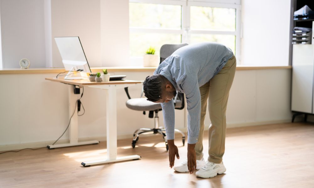 Man stretching next to his standard desk.