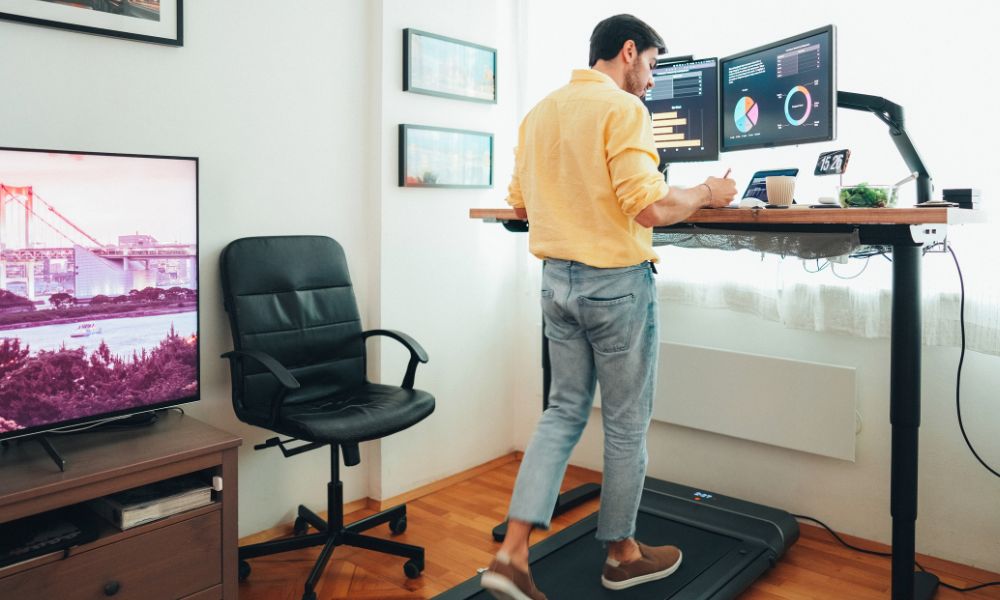 Man using treadmill while on standing desk.