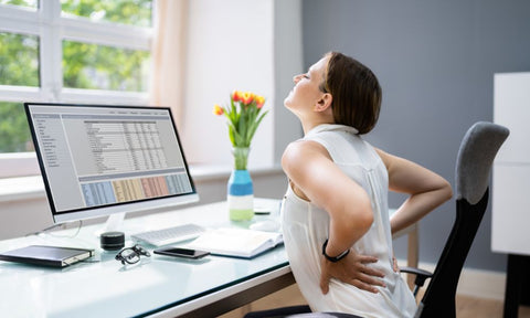 Woman sitting at her desk with a painful back.
