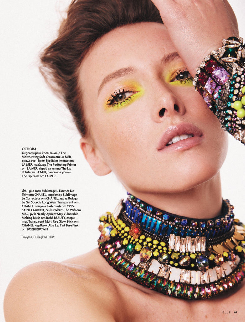 An image of a model wearing layered statement jewellery, consisting of multiple necklaces, bracelets, and rings by Jolita Jewellery. The jewellery is made with high-quality crystals, with each piece intricately designed and crafted by hand. The jewellery adds a touch of glamour and sophistication to the overall look