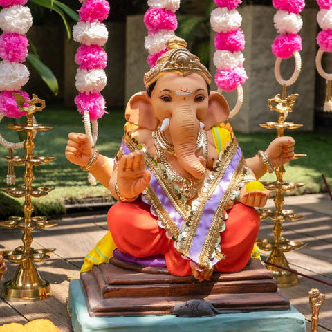 lord ganesha with prasad in hand and his mouse beside him decorated with purple satin patta