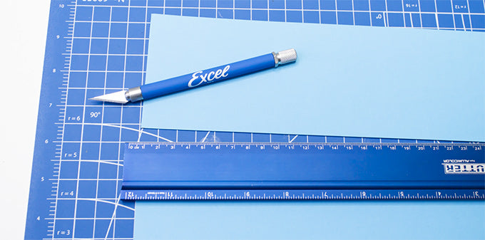 a craft knife on a cutting mat with a piece of cut paper