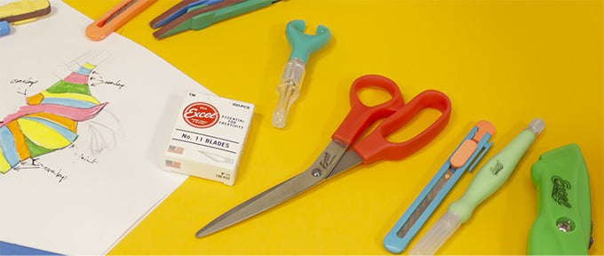 a pair of craft scissors next to a snap blade knife and other crafting tools