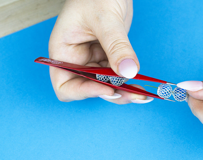 a person holding a pair of hollow point tweezers