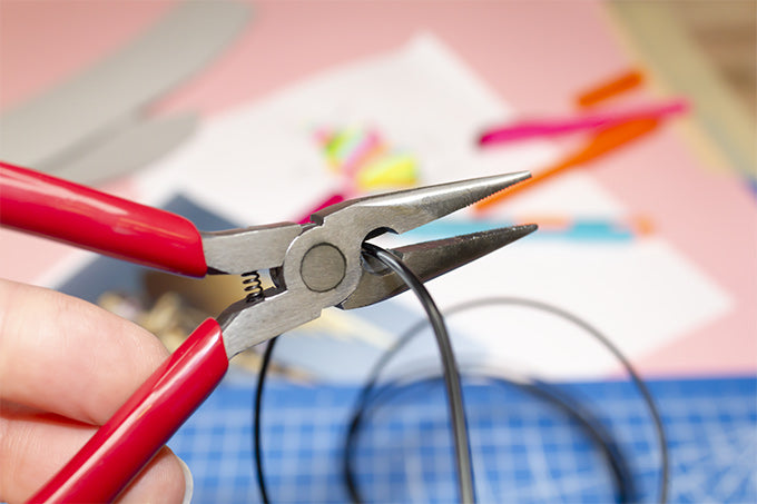 a person using pliers to cut a length of wire