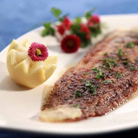 A photo of lightly fried fish served beside a small potato carved into an elegant shape.