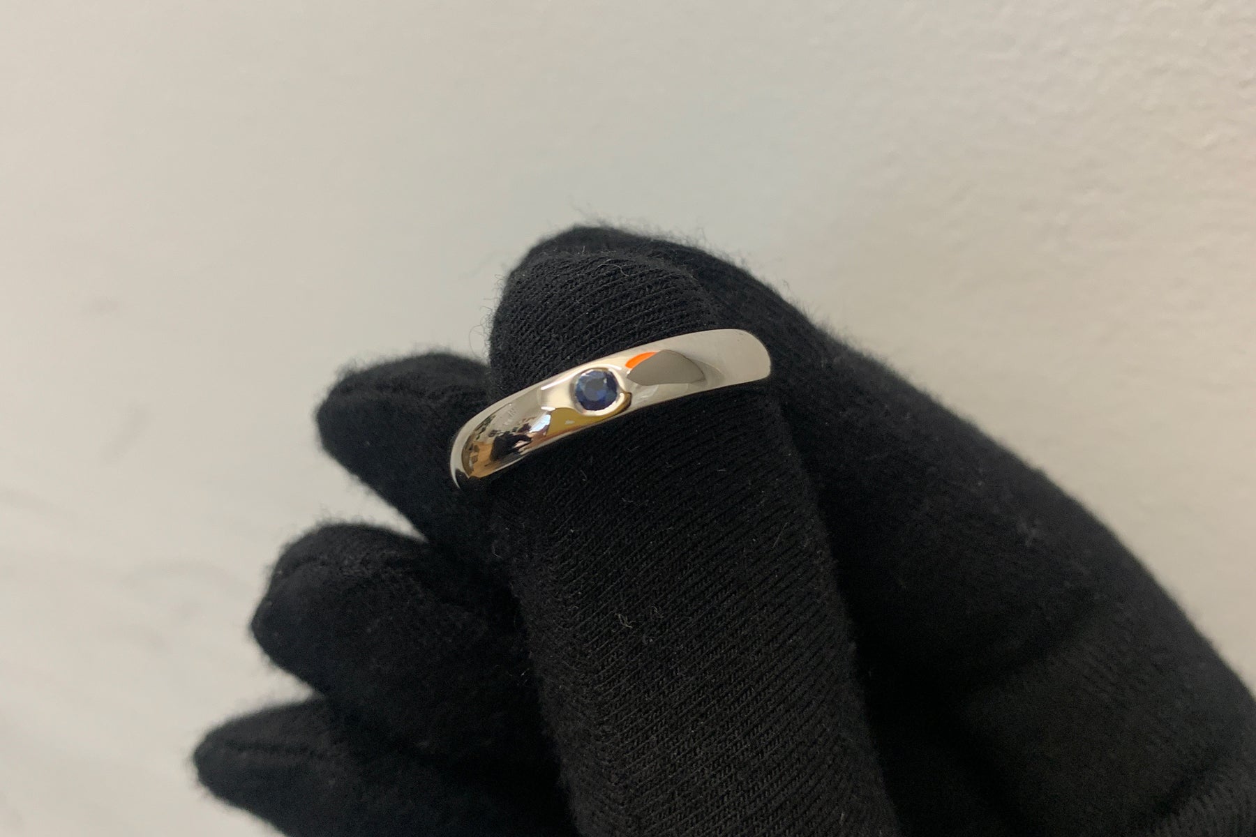 Gemmologist holding bespoke blue sapphire single stone Platinum men's wedding band from Fenton