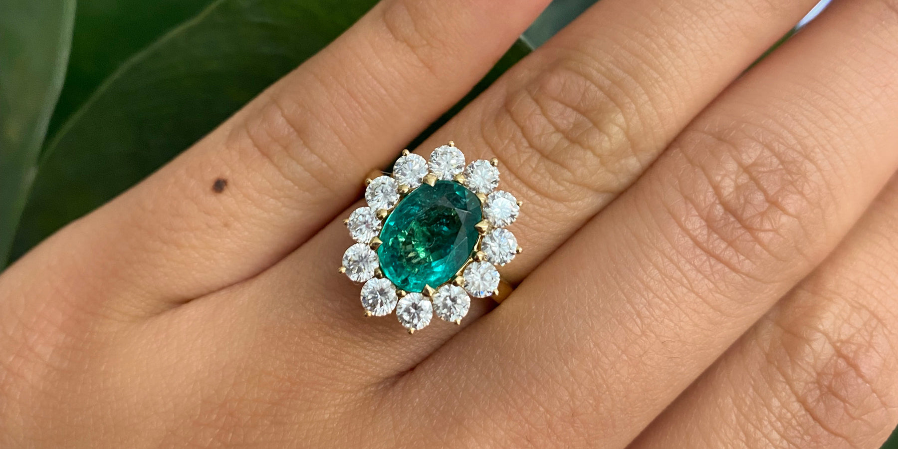 Woman wearing bespoke oval cut Emerald Star engagement ring from fine gemstone jeweller Fenton