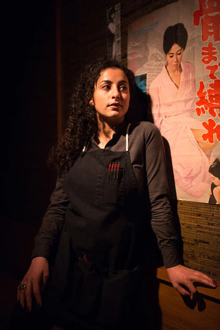 Server in a charcoal long sleeve top and black canvas apron made by Stock