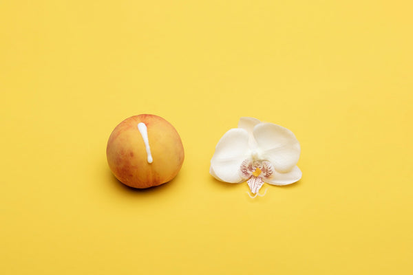 peach with white liquid and flower on yellow background