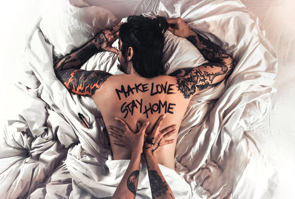 Man laying in bed with words "Make Love Stay Home" written on his back