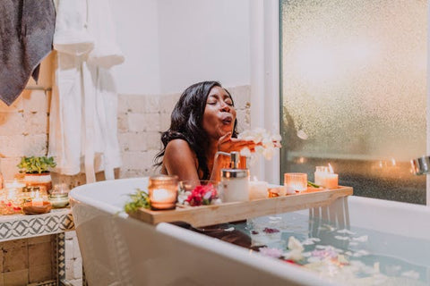 femme person of color in a tub taking care of themselves