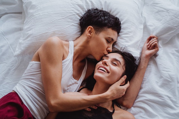 two people laying in bed kissing