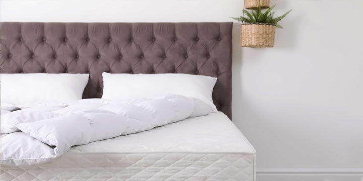 cama con sábanas y almohadas blancas con cabecera marrón