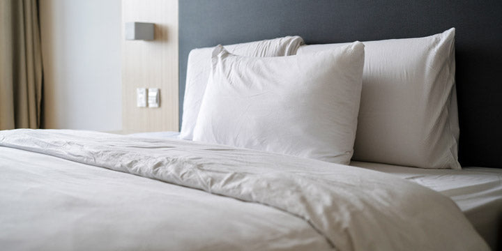 cama tendida con almohadas y sábanas blancas