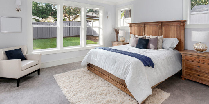 cama de madera en dormitorio con ventanas grandes