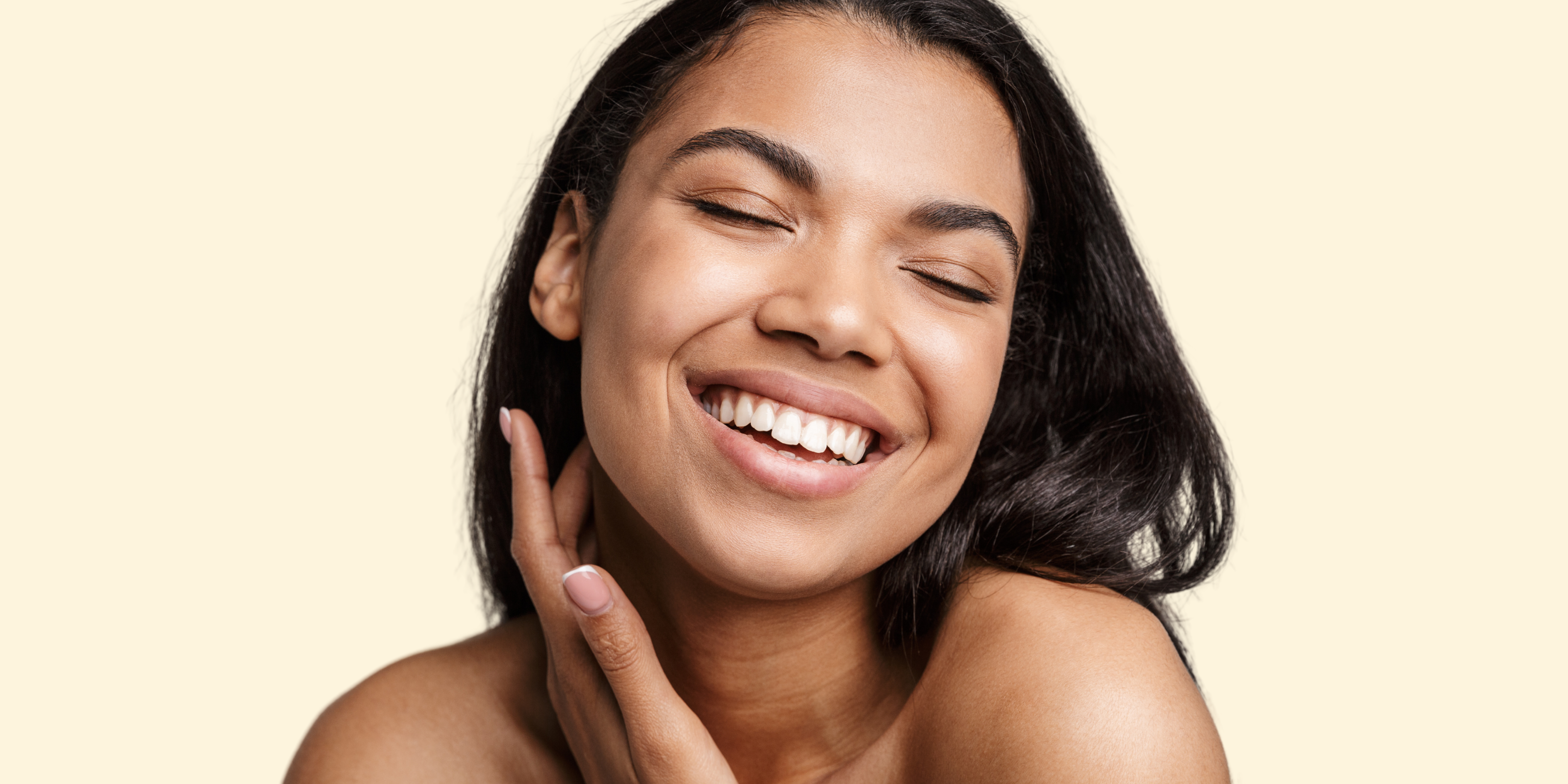 woman smiling while putting on skincare. Fighting breakouts with Glycolic Acid (AHA)