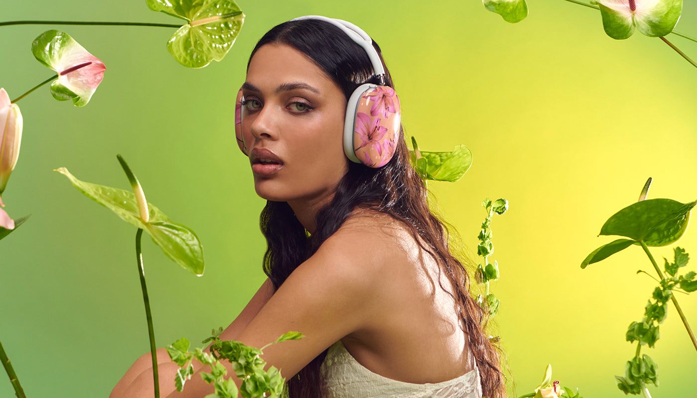 A woman wearing Airpods Max with BURGA's Secret Garden case, surrounded by plants.