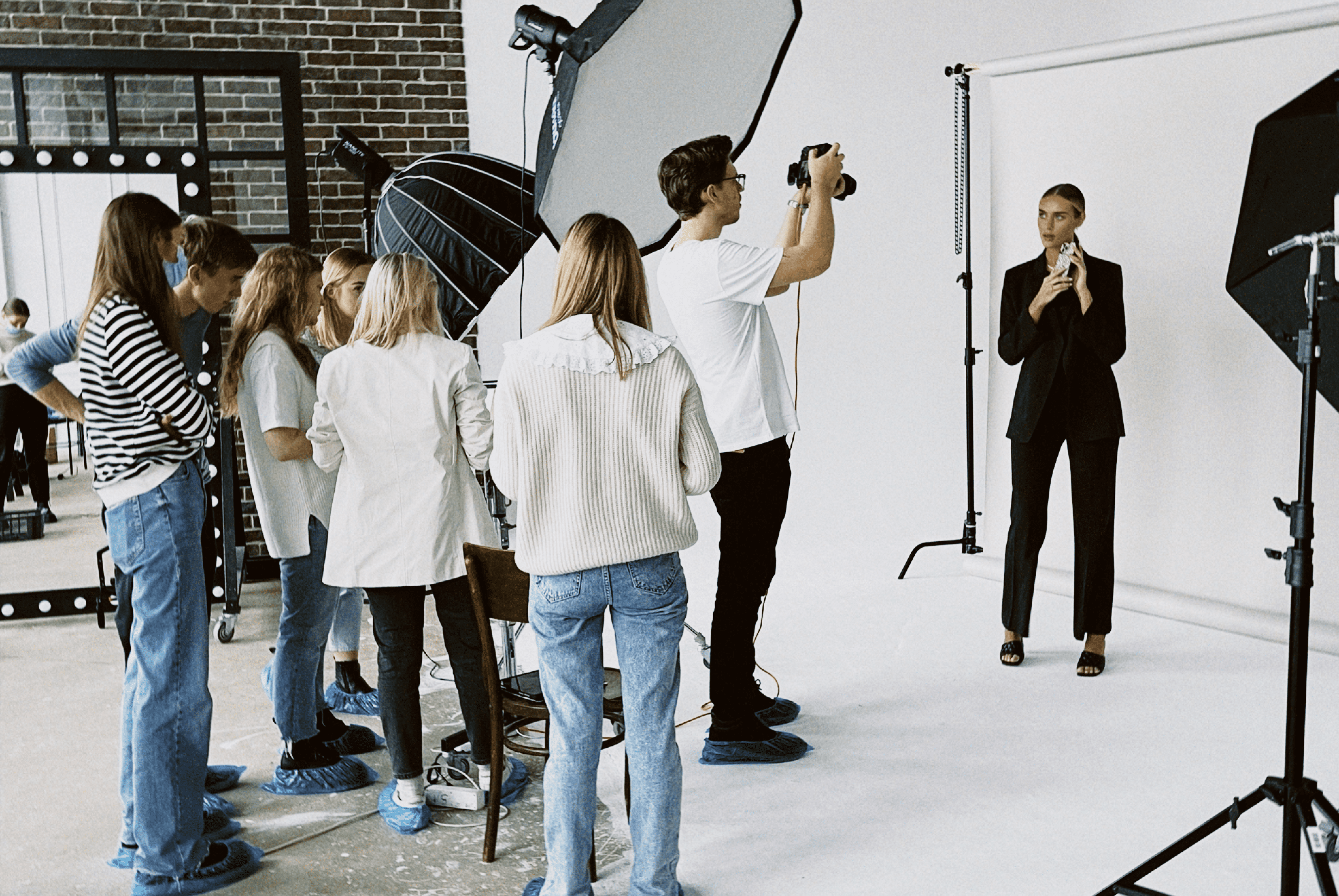 Photographer capturing a model during a photoshoot, surrounded by a team in a studio setting.