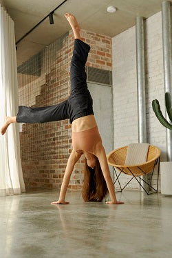 Young athletic woman doing hands stand on her porch