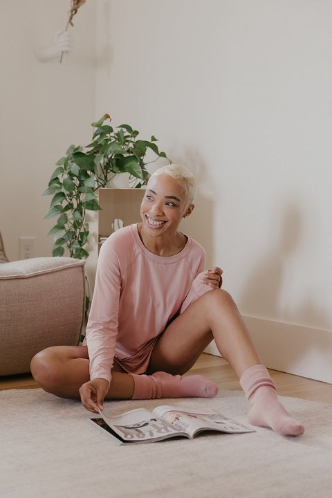 Relaxed woman in loungewear sitting on the floor and reading