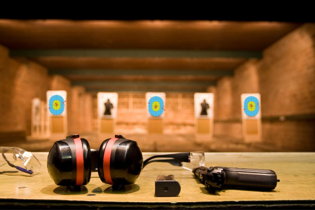 shooting range with ear and eye protection, gun magazine and gun pointed down range