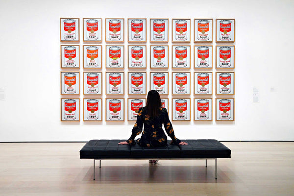 A lady in a gallery viewing Andy Warhol's Campbell's Soup Cans